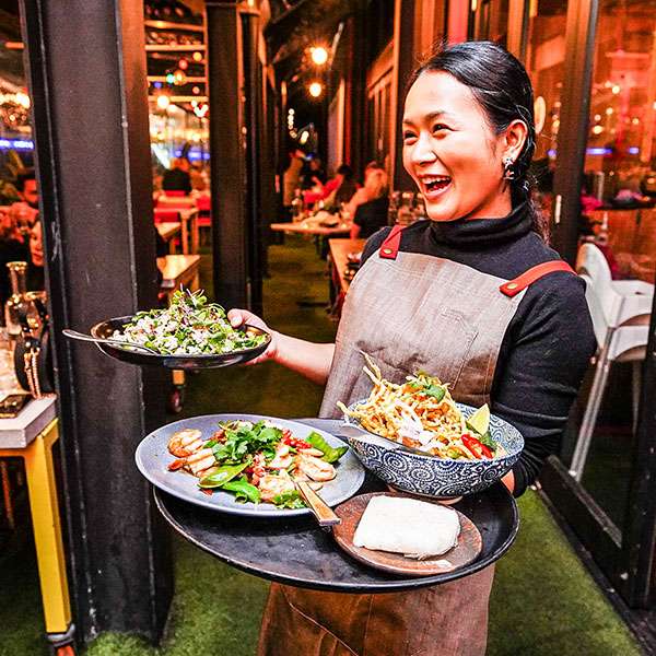 BangPop team member carrying Thai dishes through the restaurant