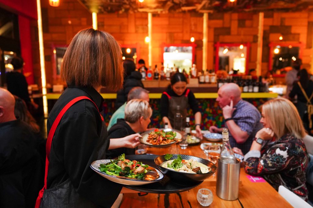 BangPop team serving shared Thai dishes to a seated event